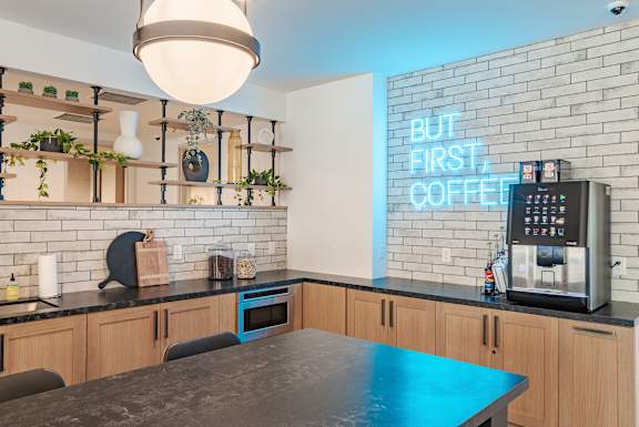 Community kitchen with neon sign and coffee station at The Yancey Apartments, Charlotte, 28217
