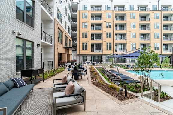 Courtyard pool deck with lounge chairs and dining areas at The Yancey Apartments, Charlotte, 28217