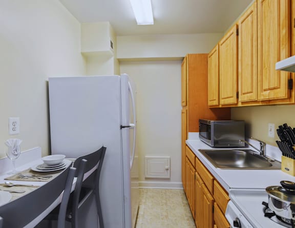 A kitchen with a white refrigerator, wooden cabinets, and a stove top oven.