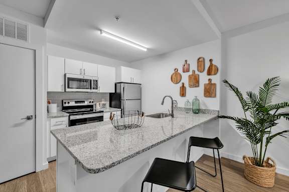 A kitchen with a granite countertop and black chairs.