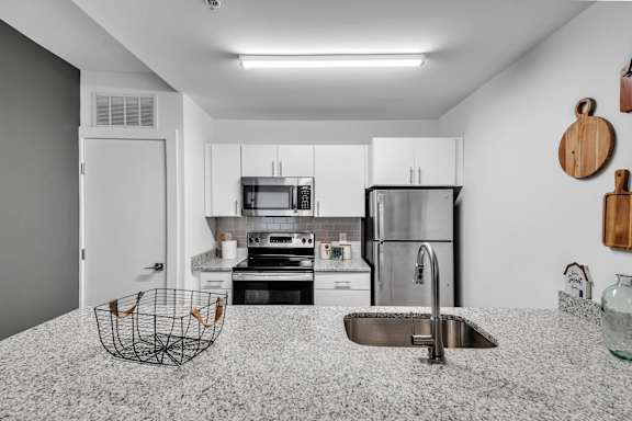 A modern kitchen with a stainless steel refrigerator, microwave, and oven.
