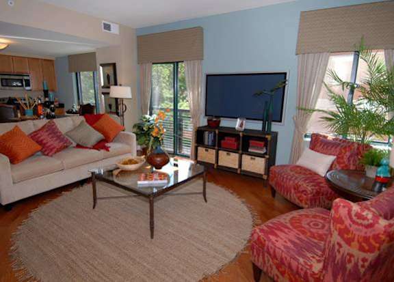 A living room with a white couch, a coffee table, and a television at Argent Apartments, Silver Spring