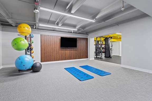 A room with a blue mat on the floor and a TV on the wall.