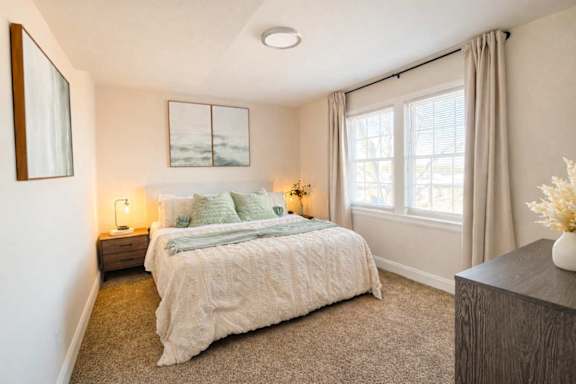 A bedroom with a large bed and a painting on the wall.