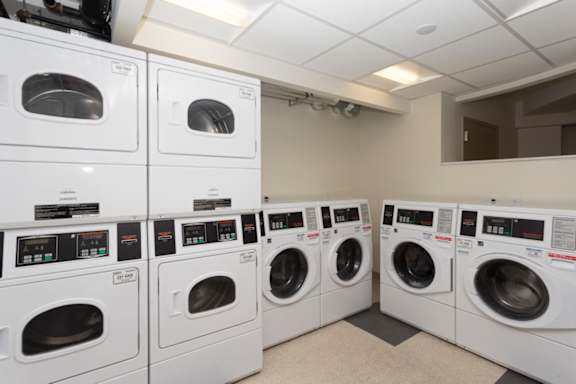A row of white front load washing machines in a laundromat at The Brittany, Washington, DC, 20015