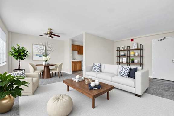 A living room with a white couch, a coffee table, and a ceiling fan.