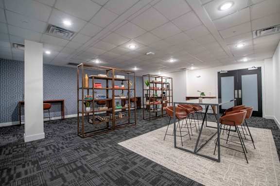 A room with a table surrounded by chairs and a bookshelf.