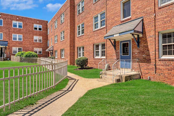 A red brick building with a white fence and a small garden in front.