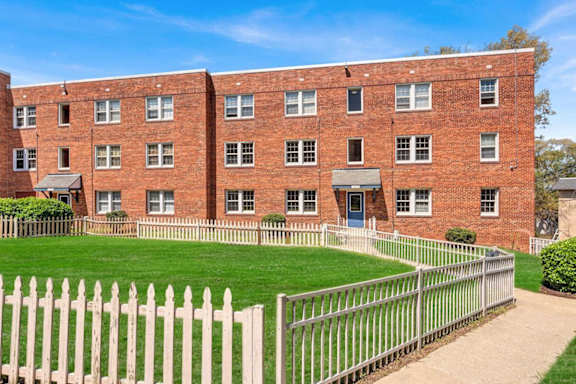 A red brick building with a white picket fence in front.