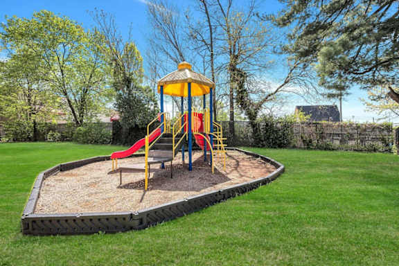 A playground with a yellow and red slide and a yellow and blue tower.