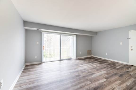 A room with a sliding glass door and wooden flooring at BellaVista Apartments in Woodbridge, VA
