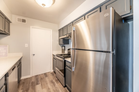 a kitchen with gray cabinets and stainless steel appliances at BellaVista Apartments in Woodbridge, VA