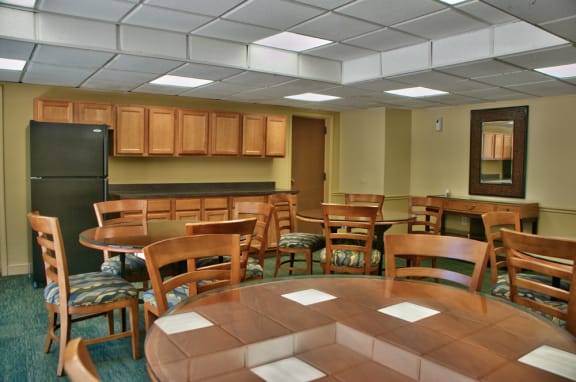 community room with wood tables and chairs and black fridge at Remington Place, Fort Washington, Maryland