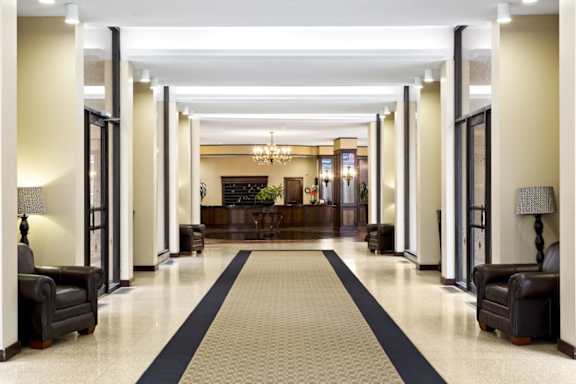 A long hallway with a black and white carpet and black furniture.