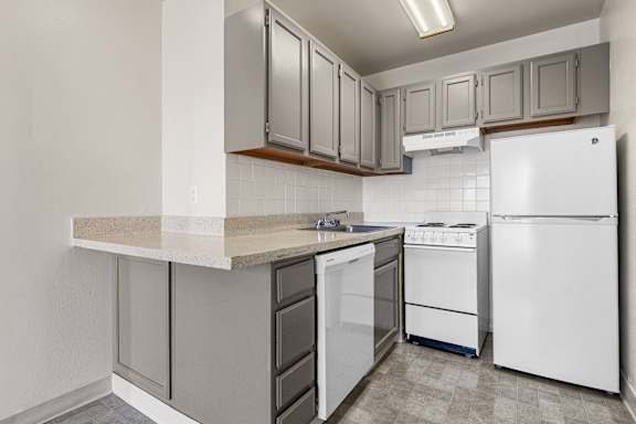 A kitchen with white appliances and grey cabinets.