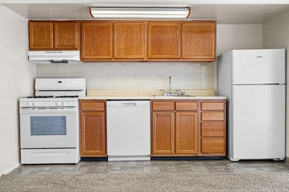 A kitchen with white appliances and wooden cabinets.
