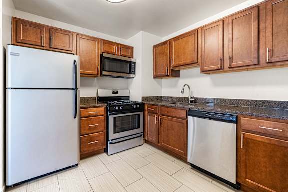 A kitchen with a white refrigerator, black stove, and brown cabinets.