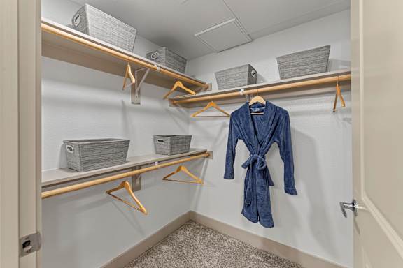 A blue robe is hanging on a hanger in a closet.