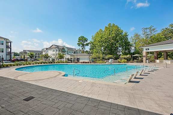A large outdoor swimming pool surrounded by a stone patio.