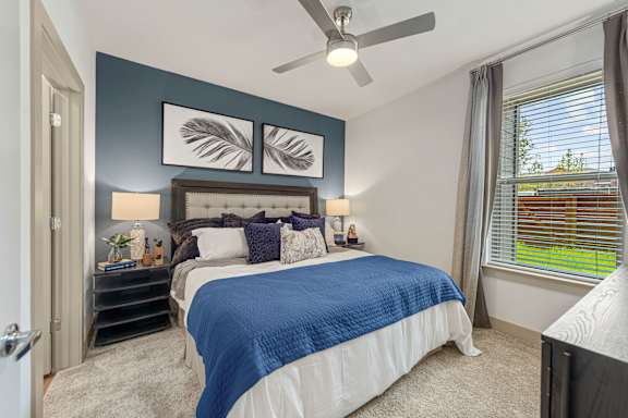 A bedroom with a bed, nightstand, and a ceiling fan.