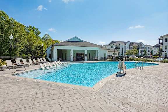 A swimming pool surrounded by lounge chairs and a building in the background.