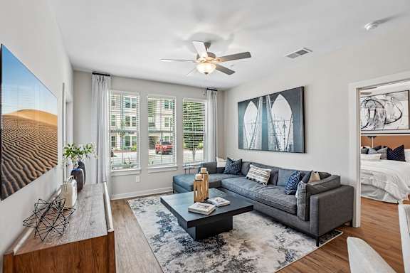 A living room with a grey couch and a ceiling fan.