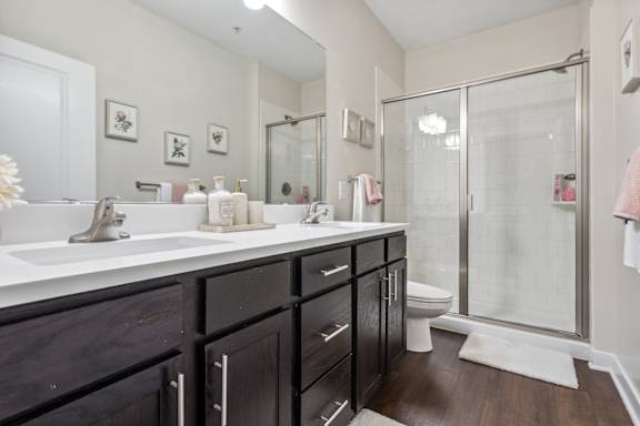 A bathroom with a white sink and a glass shower stall.at Century Hampton Roads, Suffolk Virginia