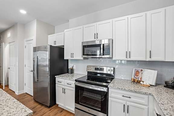 A kitchen with black appliances and white cabinets.
