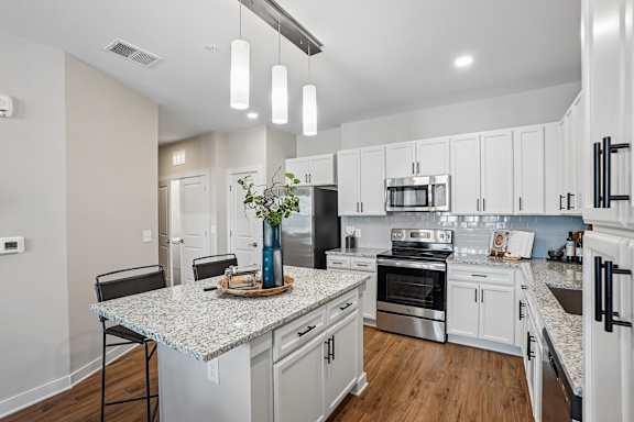 A kitchen with a granite countertop and stainless steel appliances.