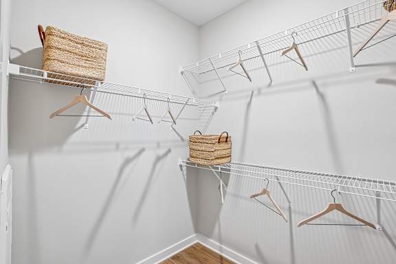 A white closet with clothes hanging on hangers.