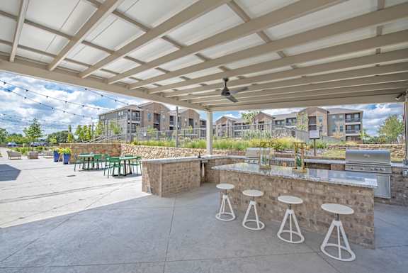 A patio with a bar and stools under a white canopy.