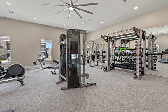 A gym with a variety of equipment including a treadmill, weights, and a bench.
