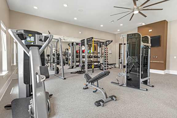 A spacious gym with a variety of equipment including treadmills, weights, and a television.