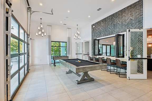 A pool table is in the middle of a room with a glass wall.