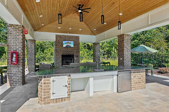 A covered patio with a fireplace and a ceiling fan.