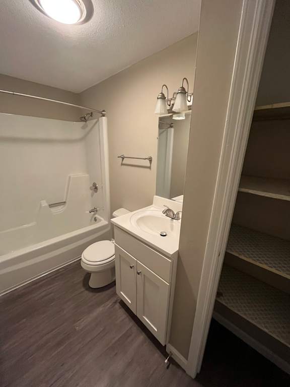 A small white bathroom with a toilet, sink, and shelves.