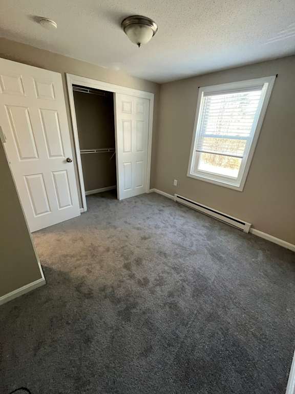 A room with a carpeted floor and a window with blinds.