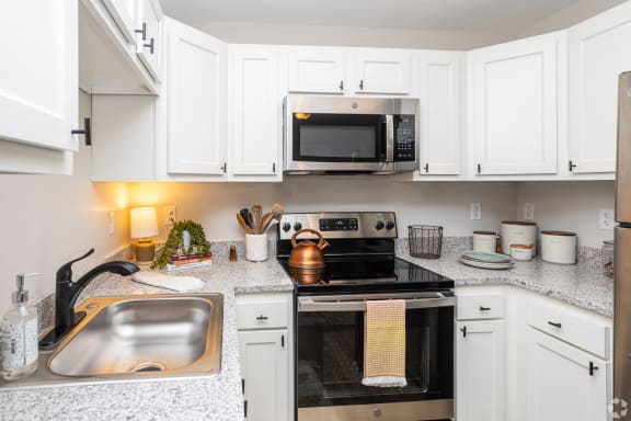 a kitchen with white cabinets and black appliances and a sink