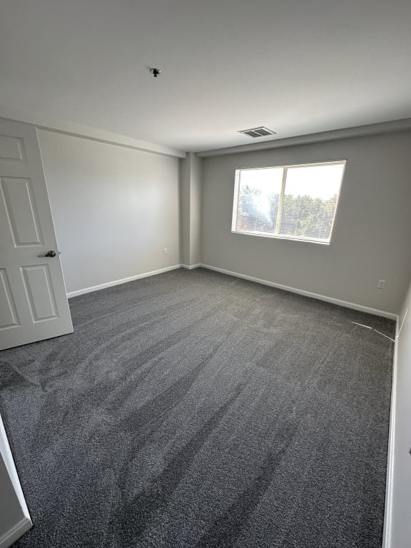 an empty room with carpet and a window at Carisbrooke at Manchester Apartments, Manchester, 03102