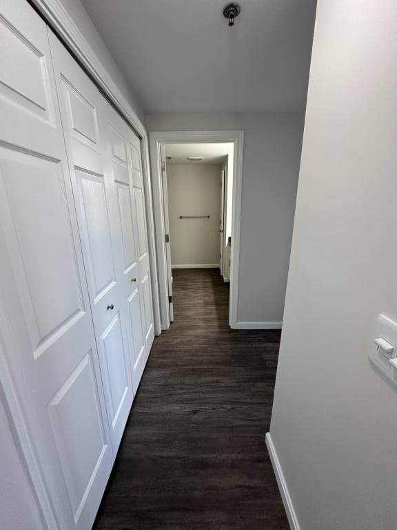 a long hallway with white cabinets and a wood floor and a door to a bedroom at Carisbrooke at Manchester Apartments, Manchester, 03102