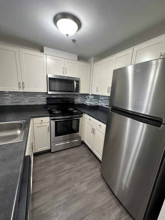 a kitchen with stainless steel appliances and white cabinets at Carisbrooke at Manchester Apartments, Manchester, NH