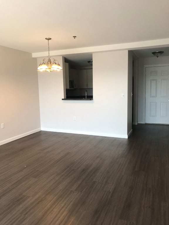 an empty living room with wood floors and a white wall at Carisbrooke at Manchester Apartments, New Hampshire
