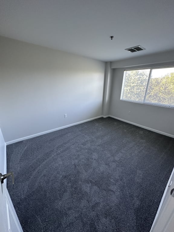 an empty room with carpet and a window at Carisbrooke at Manchester Apartments, Manchester, 03102