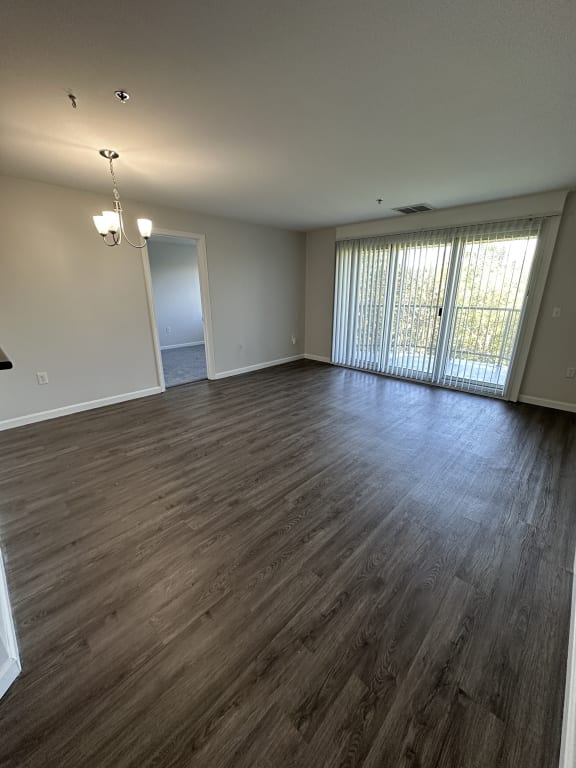 an empty living room with wood floors and a large window at Carisbrooke at Manchester Apartments, Manchester, 03102