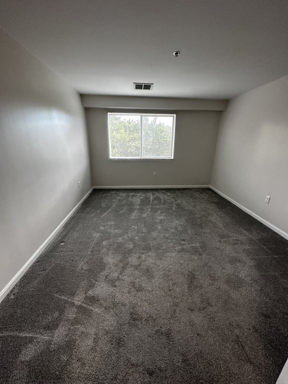 an empty room with carpet and a window at Carisbrooke at Manchester Apartments, Manchester
