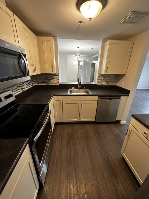 a kitchen with white cabinets and black counter tops at Carisbrooke at Manchester Apartments, Manchester, 03102