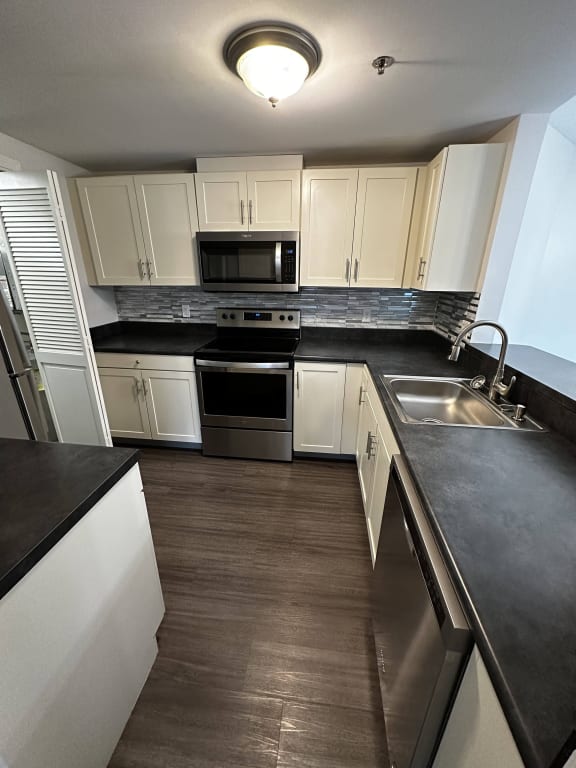 a kitchen with stainless steel appliances and white cabinets at Carisbrooke at Manchester Apartments, Manchester, NH