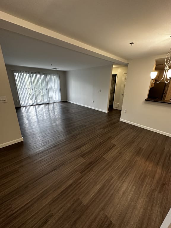 an empty living room with wood flooring and a window at Carisbrooke at Manchester Apartments, Manchester, NH