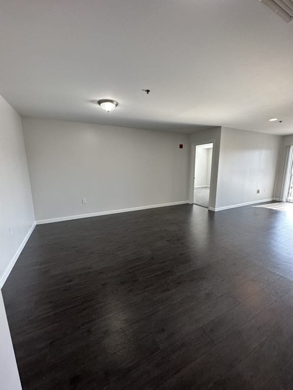 an empty living room with white walls and wood floors at Carisbrooke at Manchester Apartments, New Hampshire, 03102