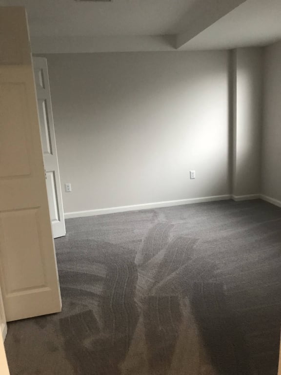a bedroom with a carpeted floor and a white wall at Carisbrooke at Manchester Apartments, Manchester, New Hampshire